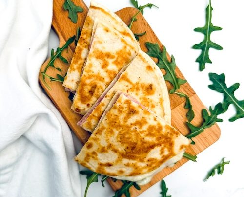 Ham and cheese quesadilla on a cutting board.