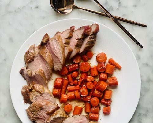 Sliced pork and carrots on a plate.