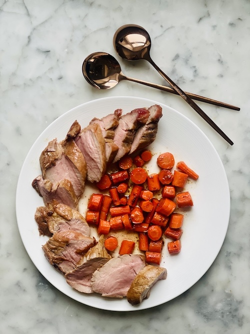 Sliced pork and carrots on a plate.