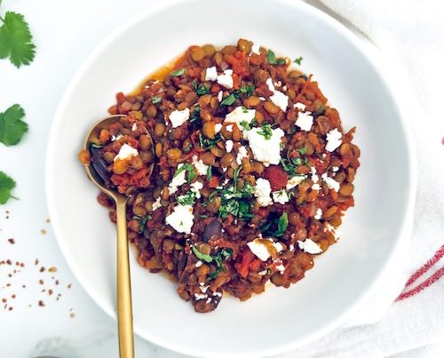 Baked lentils in a bowl topped with feta.
