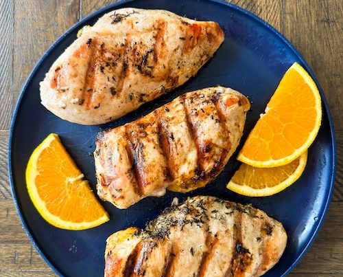 Orange marinated chicken on a plate.