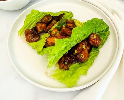 Bourbon chicken in lettuce wraps on a plate.
