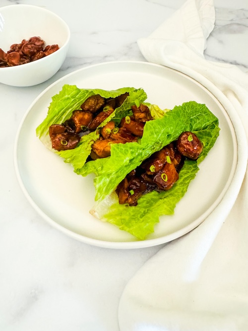 Bourbon chicken in lettuce wraps on a plate.