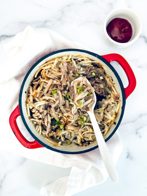 Breakfast hamburger hash browns in a cast iron skillet.