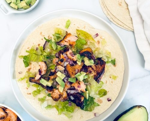 Grilled salmon taco with lettuce and avocado.