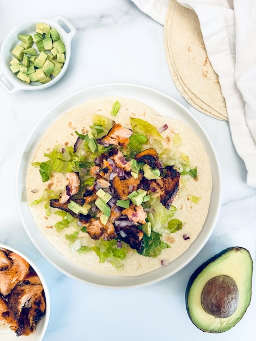 Grilled salmon taco with lettuce and avocado.