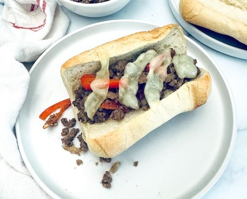 Ground beef cheesesteak in a roll.