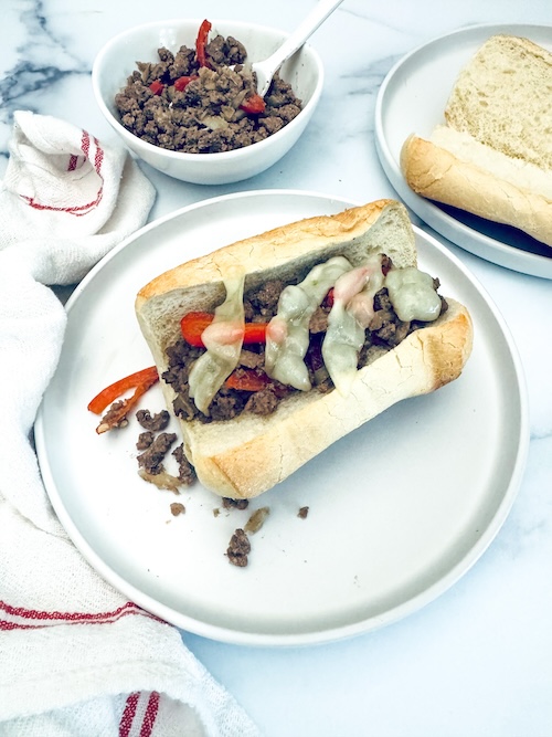 Ground beef cheesesteak in a roll.