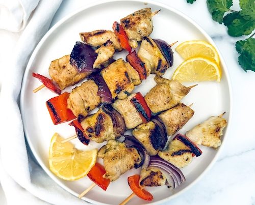 Lemon pepper chicken kebobs on a plate.