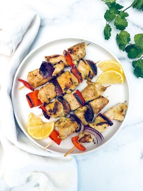 Lemon pepper chicken kebobs on a plate.