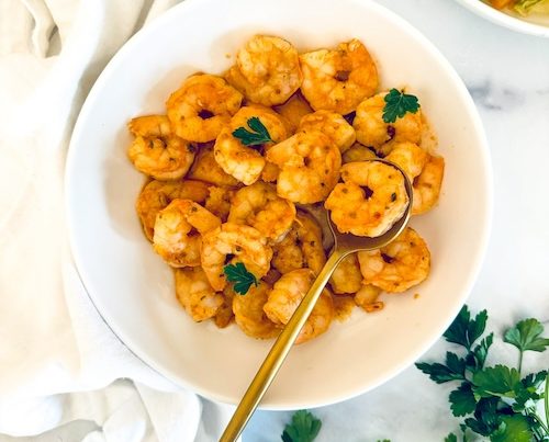 A bowl fill of mediterranean seasoned shrimp.
