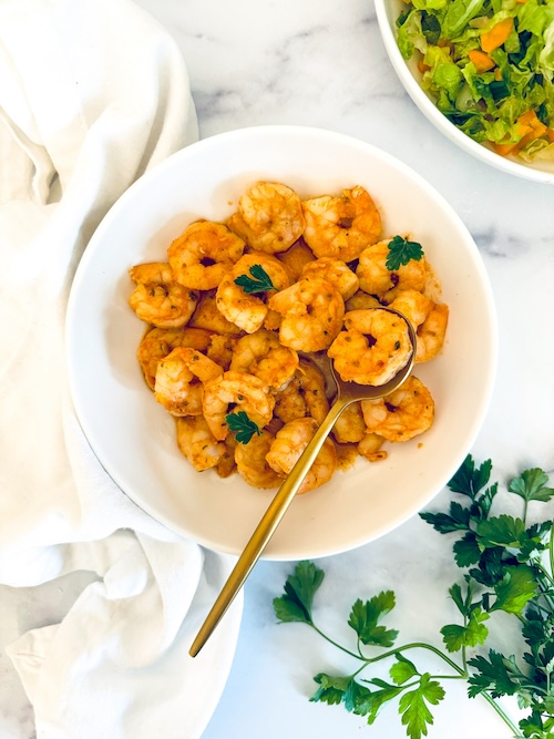 A bowl fill of mediterranean seasoned shrimp.