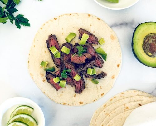 Skirt steak taco on a marble counter.