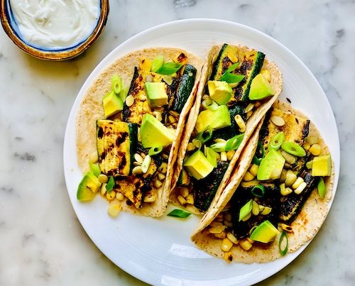 Corn and zucchini tacos on a plate.