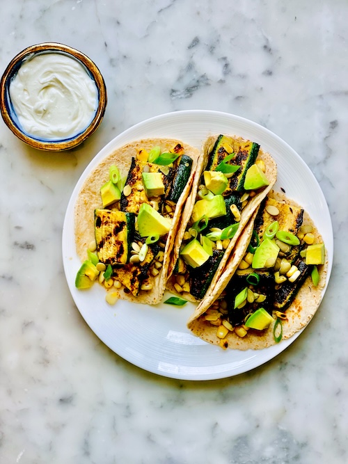 Corn and zucchini tacos on a plate.