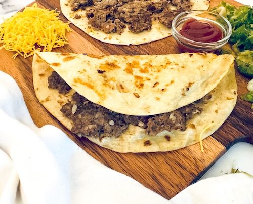 Smash burger tacos on a cutting board.
