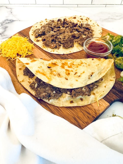 Smash burger tacos on a cutting board.