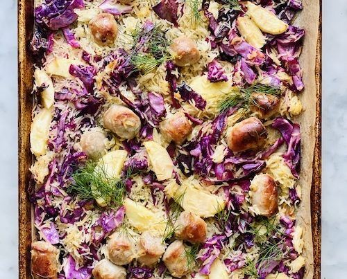 A sheet pan filled with bratwurst and apples.