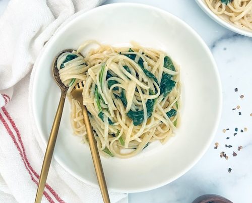 Creamy spaghetti and baby spinach in a bowl.