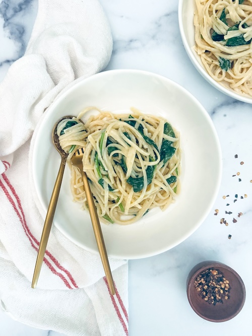 Creamy spaghetti and baby spinach in a bowl.
