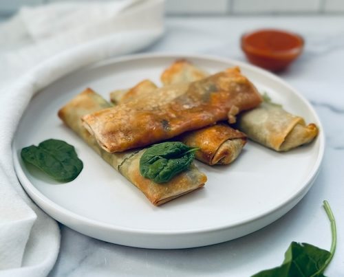 Vegan spinach pizza egg rolls on a plate.
