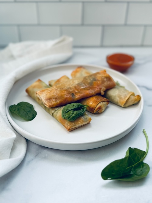 Vegan spinach pizza egg rolls on a plate.