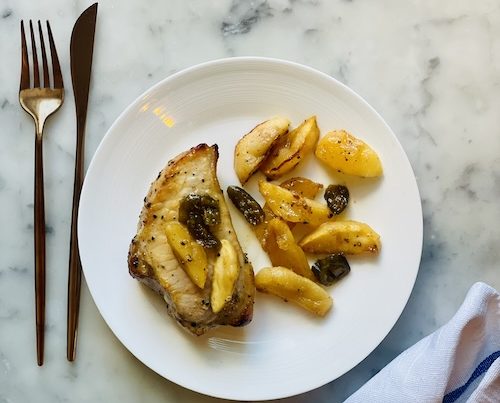 Pork chop and apples on a plate.