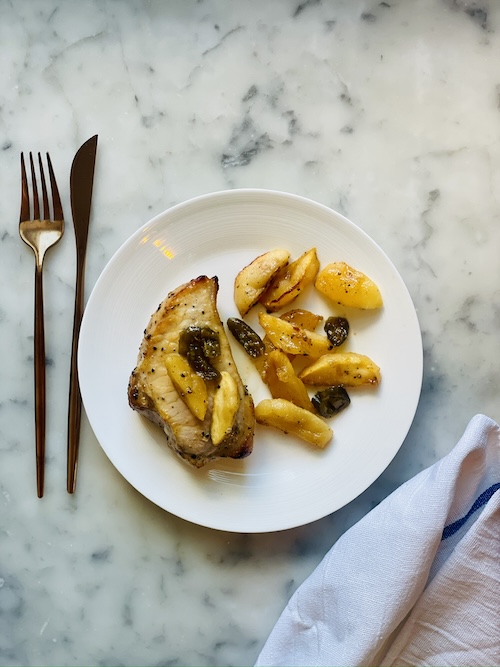 Pork chop and apples on a plate.