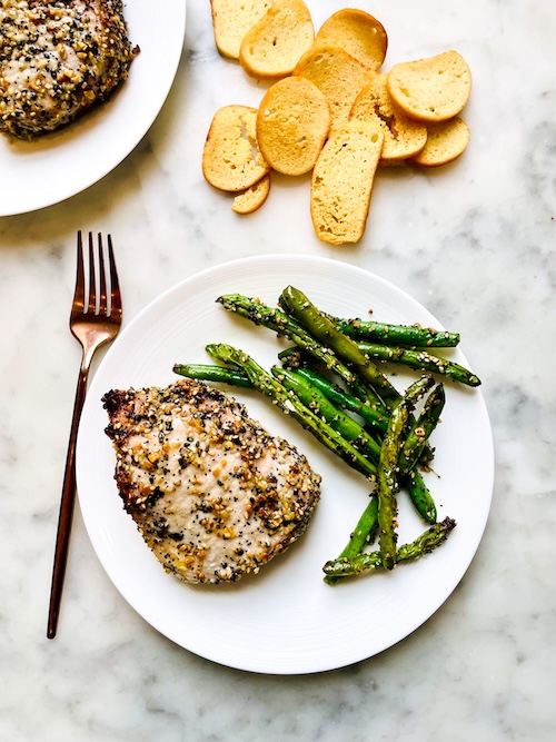 Everything bagel pork chop on a plate with green beans.