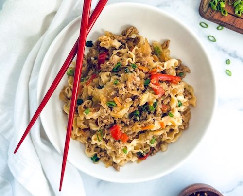 Chicken ramen stir fry in a bowl with chopsticks.
