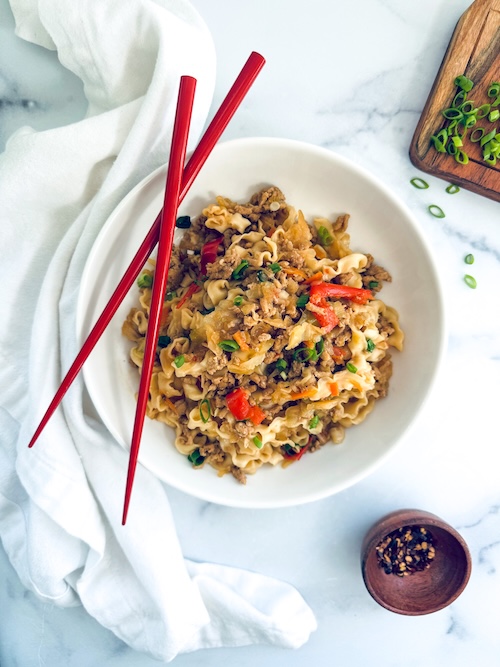Chicken ramen stir fry in a bowl with chopsticks.