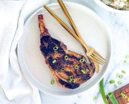 Grilled bone-in pork chop on a plate.