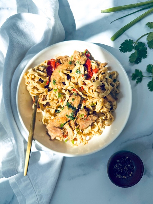 Thai peanut chicken over a bowl of noodles.