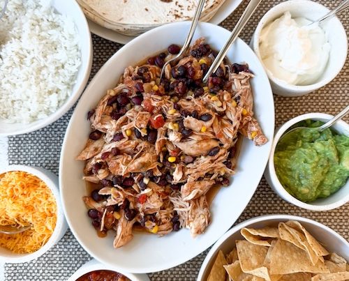 Salsa chicken with bowls of toppings.