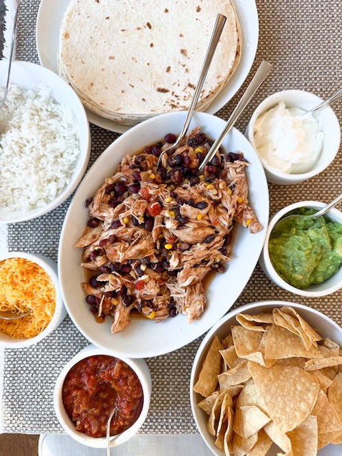 Salsa chicken with bowls of toppings.