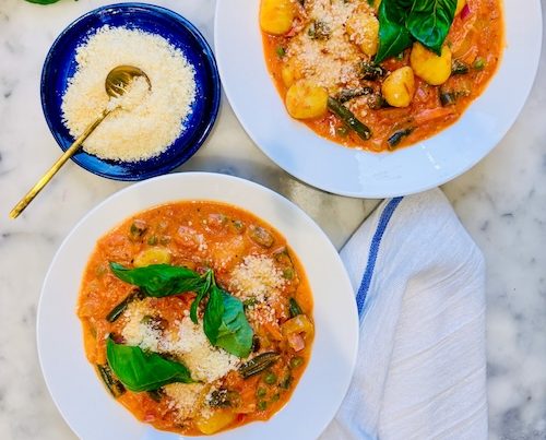Two bowls of vegetable soup with gnocchi.