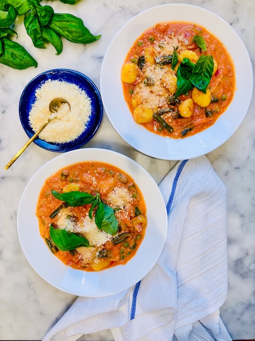 Two bowls of vegetable soup with gnocchi.