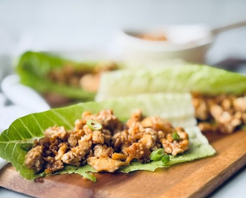 Asian tofu lettuce wraps on a wood board.