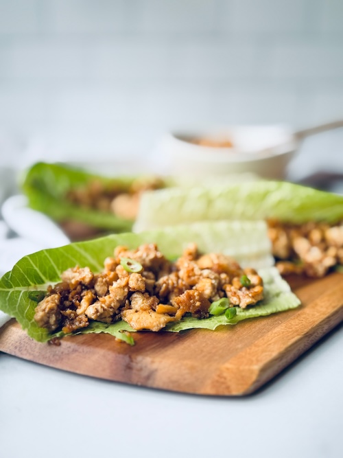 Asian tofu lettuce wraps on a wood board.