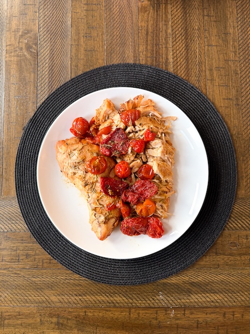 Turkey tenderloin with tomatoes on a plate.