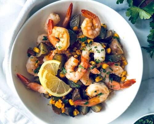 Shrimp boil in a bowl with lemon slices.