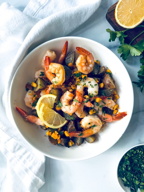 Shrimp boil in a bowl with lemon slices.