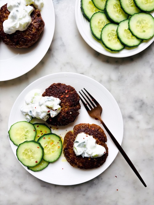Grilled lamb patties and sliced cucumbers.