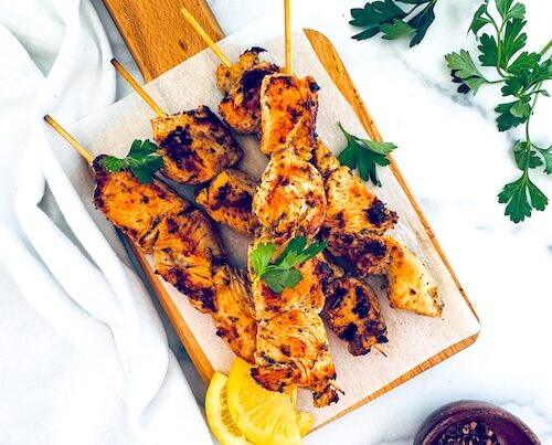 Chicken souvlaki skewers on a wooden board.