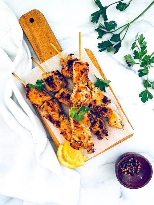 Chicken souvlaki skewers on a wooden board.