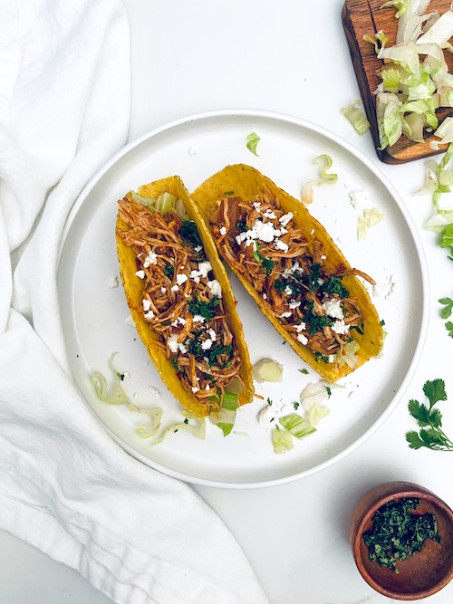 Two crunchy chicken tacos on a plate.