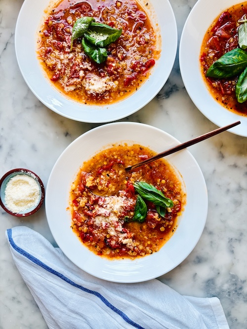 Three bowls of tomato lentil soup.