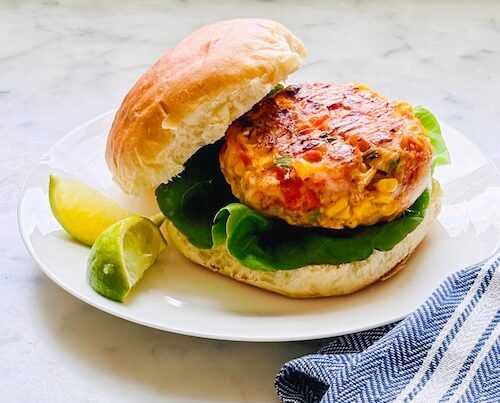 Shrimp corn cake on a bun with lettuce.
