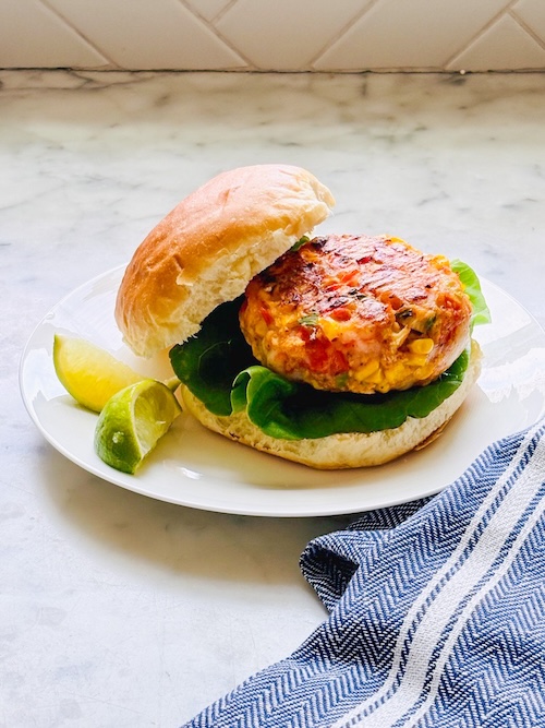 Shrimp corn cake on a bun with lettuce.