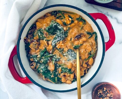 Cast iron pot of tuscan white beans with kale.